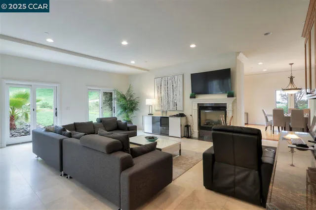 a living room with furniture a fireplace a flat screen tv and a large window
