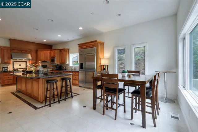 a kitchen with stainless steel appliances kitchen island granite countertop a table chairs sink and cabinets