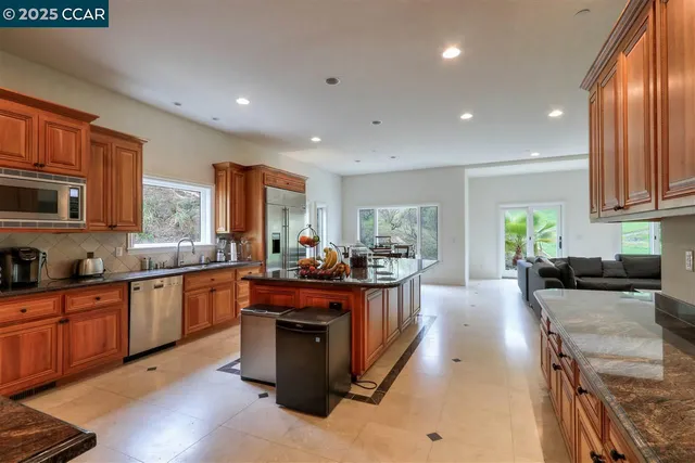 a kitchen with stainless steel appliances granite countertop a stove top oven a sink dishwasher a dining table and chairs with wooden floor