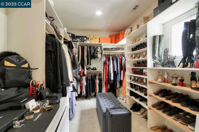 a view of walk in closet with clothes and shoes