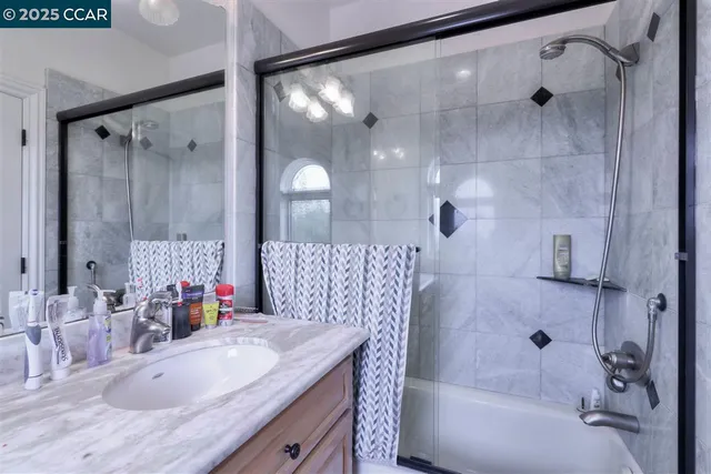 a bathroom with a granite countertop shower sink vanity and mirror