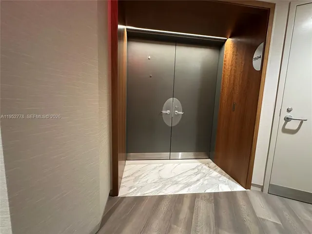 a view of a hallway with wooden floor and a bathroom