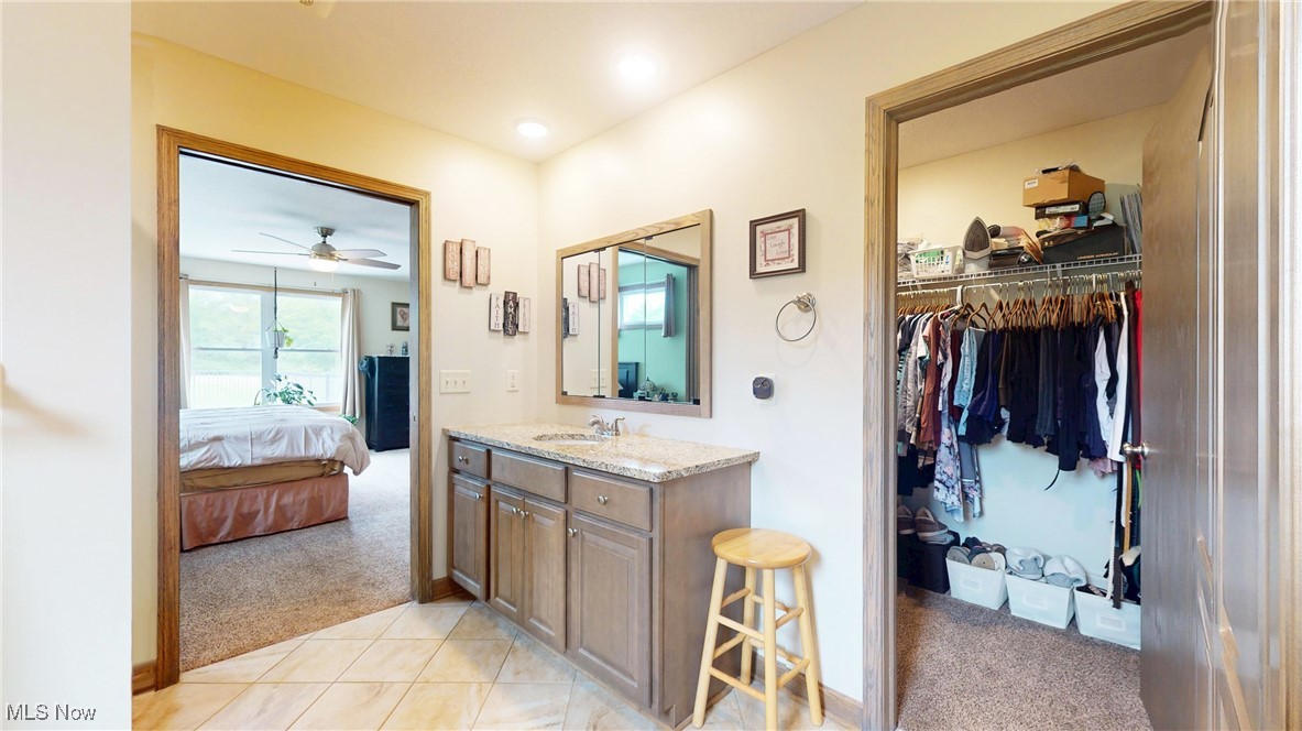 961 Industry Road Atwater, OH 44201 - Photo 18 of 50 Ensuite bathroom featuring vanity, ceiling fan, a walk in closet, and tile patterned flooring