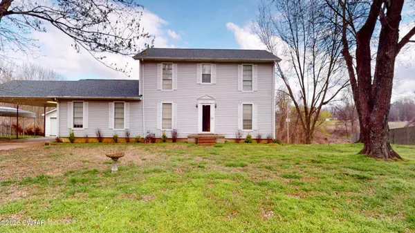 a brick house next to a yard with a large tree