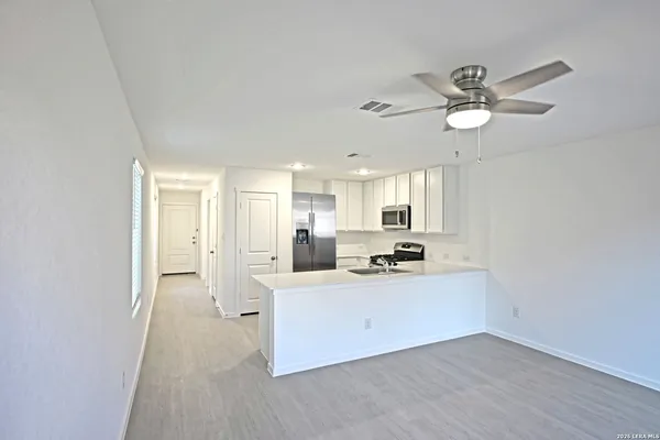 a kitchen with stainless steel appliances a sink a stove a refrigerator cabinets and a dining table