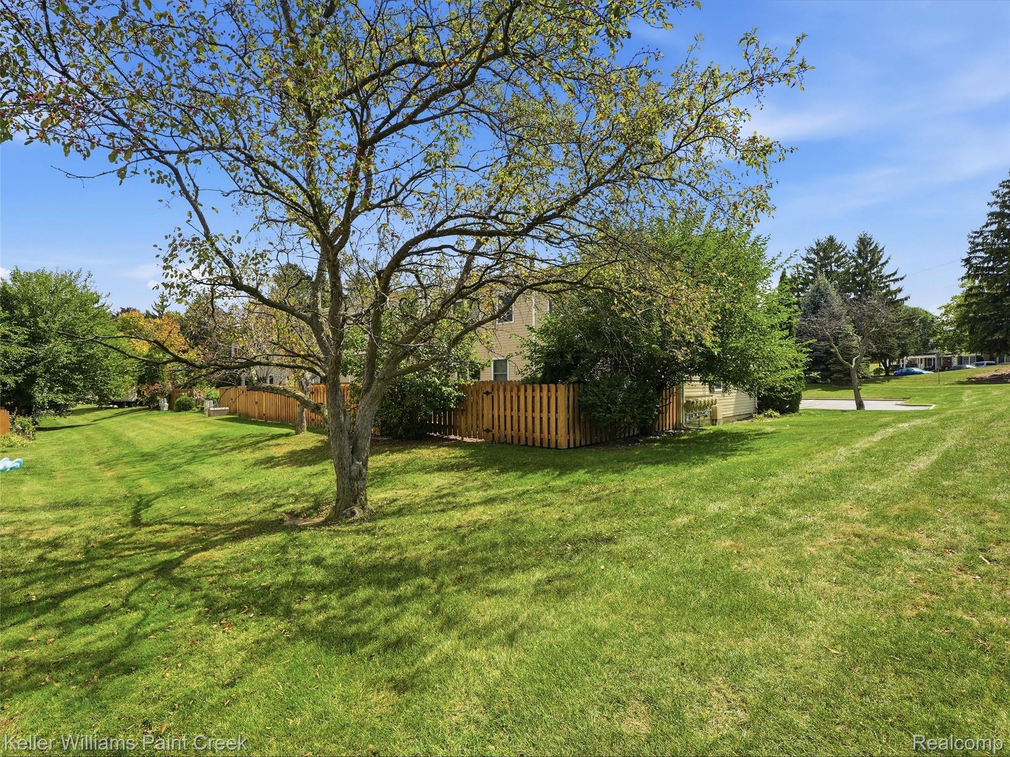 1208 Lear Court Rochester, MI 48307 - Photo 24 of 28 Expansive green lawn with mature trees and a wood picket fence