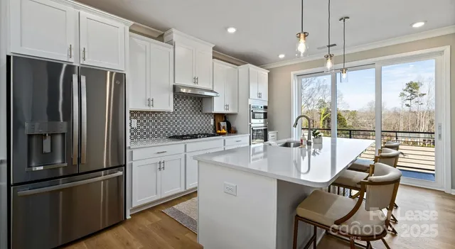 a kitchen with stainless steel appliances granite countertop a refrigerator a sink dishwasher a stove and white countertops with wooden floor