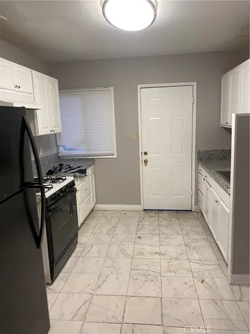 a kitchen with granite countertop a stove a sink and a refrigerator