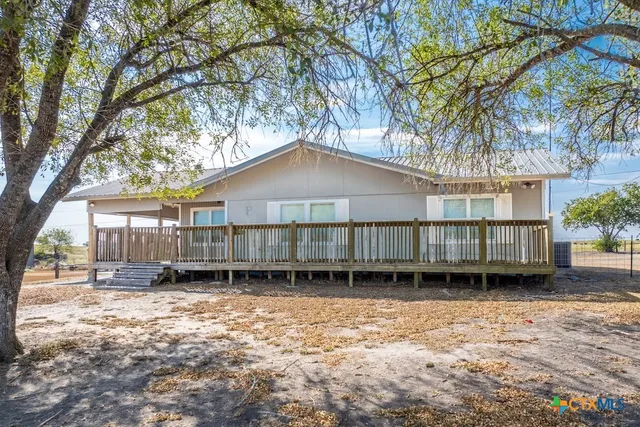 a backyard of a house with a large tree and wooden fence