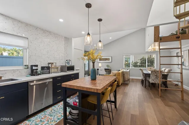 a open dining room with stainless steel appliances kitchen island granite countertop a table chairs and a refrigerator