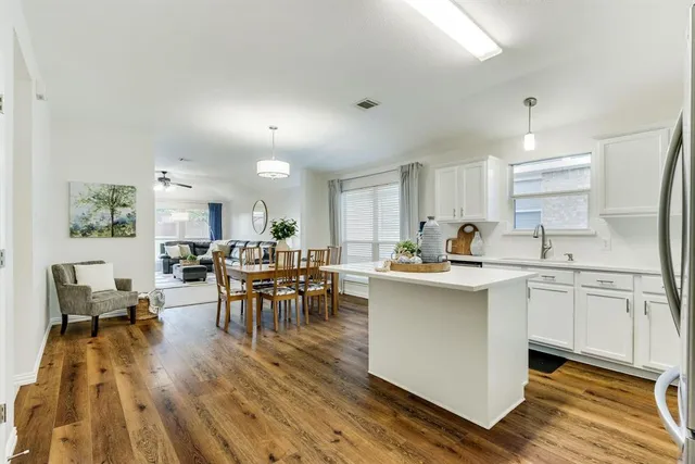 a kitchen that has a lot of cabinets in it with stainless steel appliances granite countertop a stove a sink a dining table and chairs with wooden floor