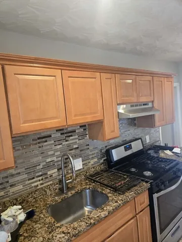 a kitchen with granite countertop a sink a stove and cabinets