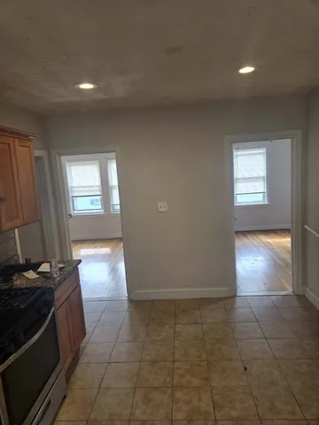 a view of an empty room and a kitchen