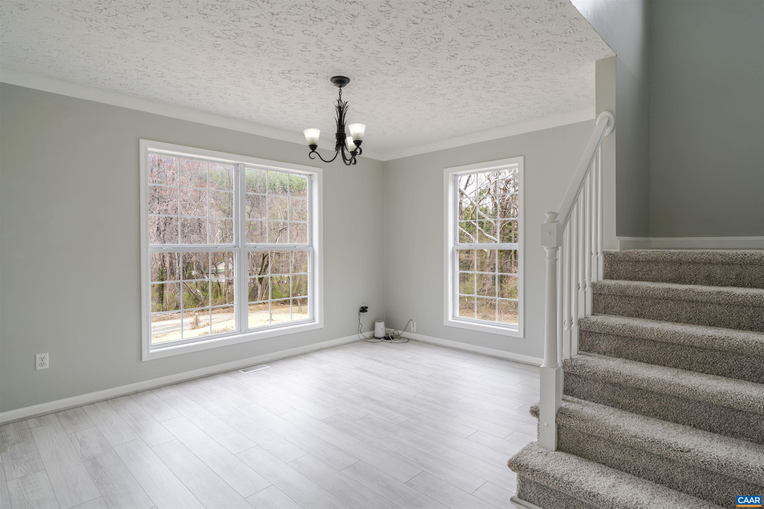 5860 Bearwood Road Crozet, VA 22932 - Photo 29 of 67 a view of an empty room with wooden floor chandeliers and a window