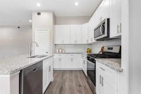 a kitchen with granite countertop a sink stove and cabinets
