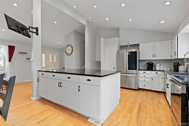 a large kitchen with stainless steel appliances kitchen island granite countertop a stove and a white cabinets