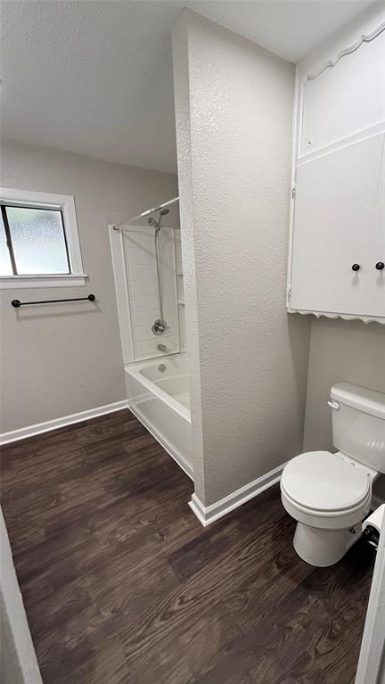 1309 Anna Street Denton, TX 76201 - Photo 12 of 13 Bathroom featuring a textured wall, dark wood-type flooring, shower / bathtub combination, and a textured ceiling