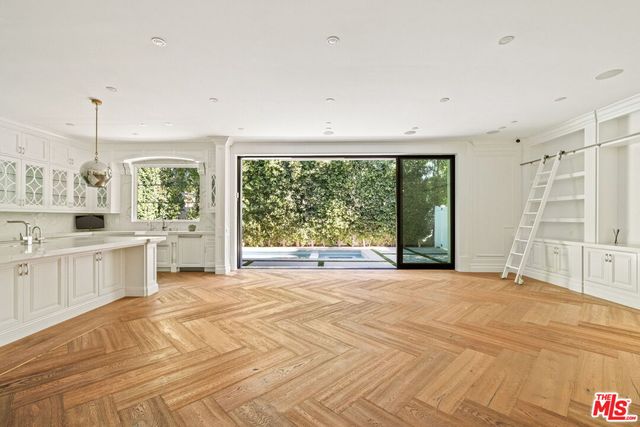 a view of an empty room with a window and a kitchen