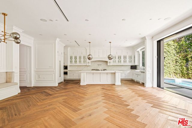 a large white kitchen with kitchen island a stove a sink and cabinets