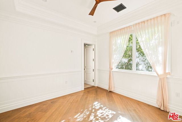 a view of empty room with wooden floor and fan