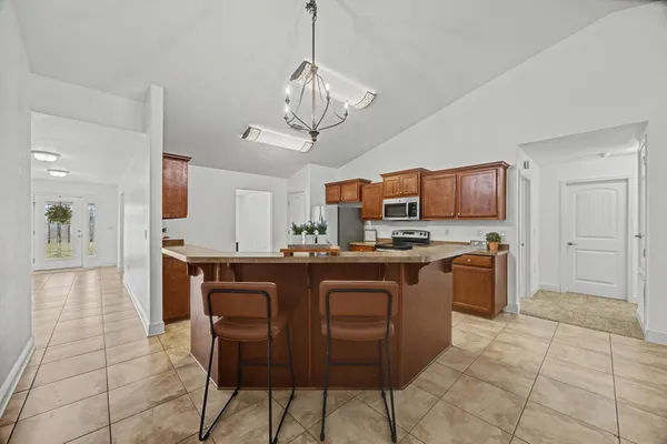 a kitchen with stainless steel appliances granite countertop a sink a stove a refrigerator cabinets and chairs