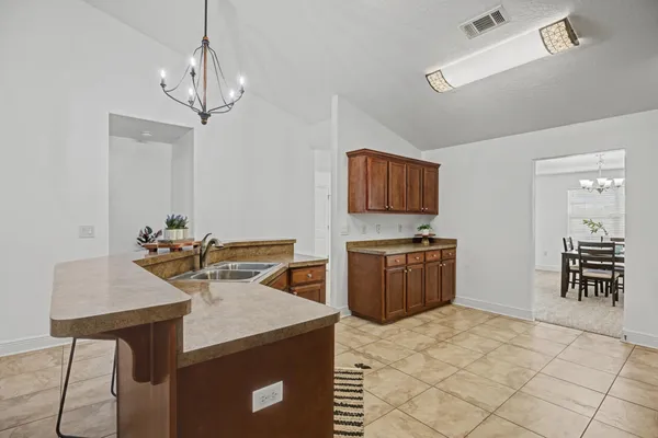 a kitchen with stainless steel appliances granite countertop a stove a refrigerator a sink a dining table and chairs with wooden floor