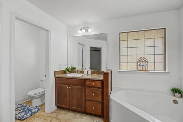 a spacious bathroom with a granite countertop double vanity sink a mirror a lamp a bathtub and vanity