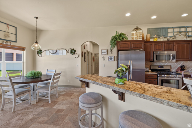 4635 East Sunny Acres Lane Moab, UT 84532 - Photo 44 of 56 Kitchen with a granite-top breakfast bar, stainless steel appliances, dark wood-finish cabinetry, and an arched doorway