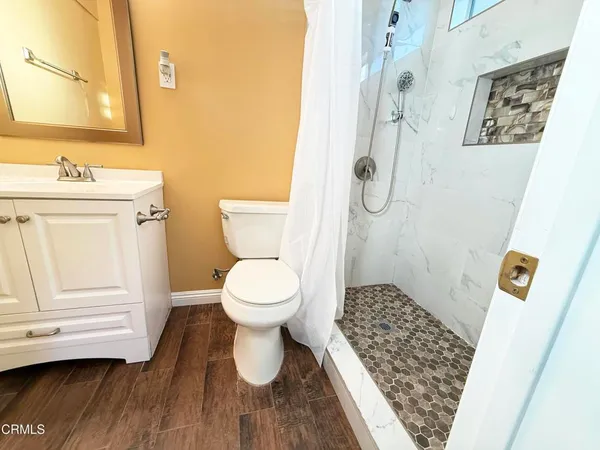 a bathroom with a toilet a sink and wooden floor