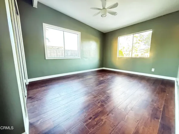 an empty room with wooden floor and windows