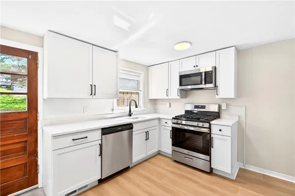 a kitchen with stainless steel appliances a stove a sink a microwave a dining table and chairs