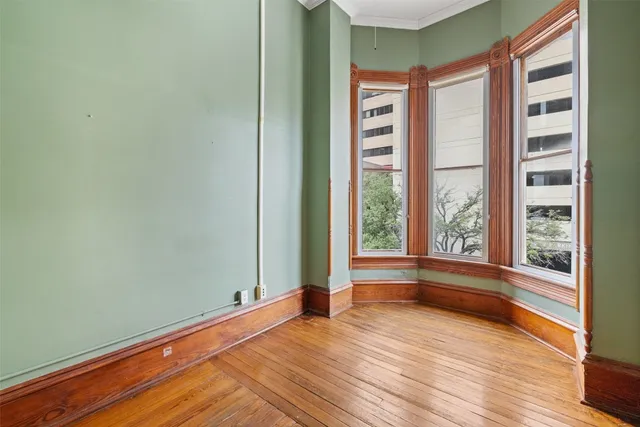 an empty room with wooden floor chandelier and windows