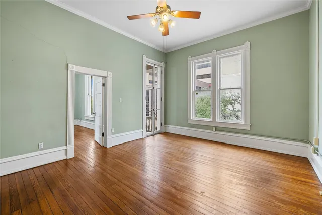 a view of empty room with wooden floor and fan