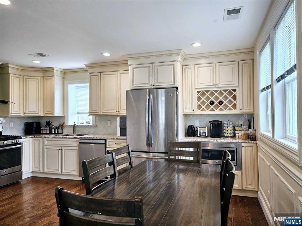 a kitchen with granite countertop a stove a sink dishwasher a refrigerator and cabinets with wooden floor