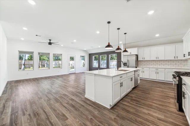 a large kitchen with stainless steel appliances granite countertop a lot of counter space and wooden floors
