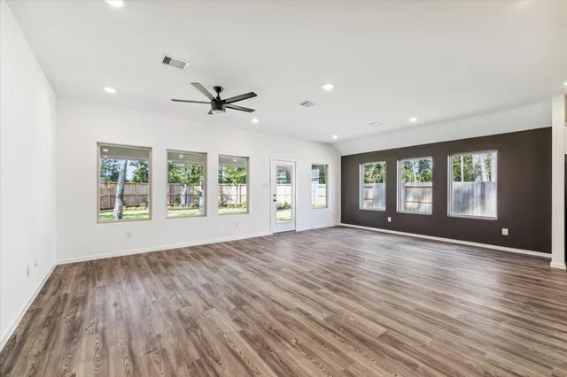 a view of an empty room with a window and wooden floor