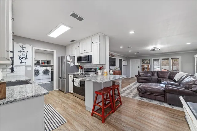 a living room with stainless steel appliances kitchen island granite countertop furniture wooden floor and a view of kitchen