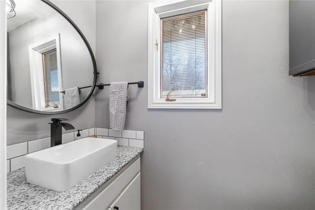 a bathroom with a granite countertop sink and a mirror