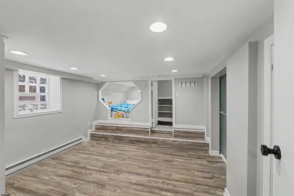 a view of an empty room with wooden floor and window