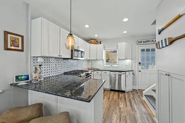 a kitchen with kitchen island granite countertop a sink cabinets and wooden floor