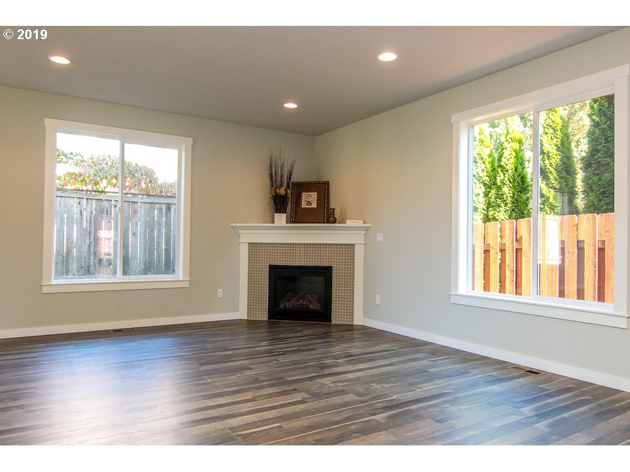 3002 Northeast 171st Street Ridgefield, WA 98642 - Photo 6 of 32 an empty room with wooden floor fireplace and windows