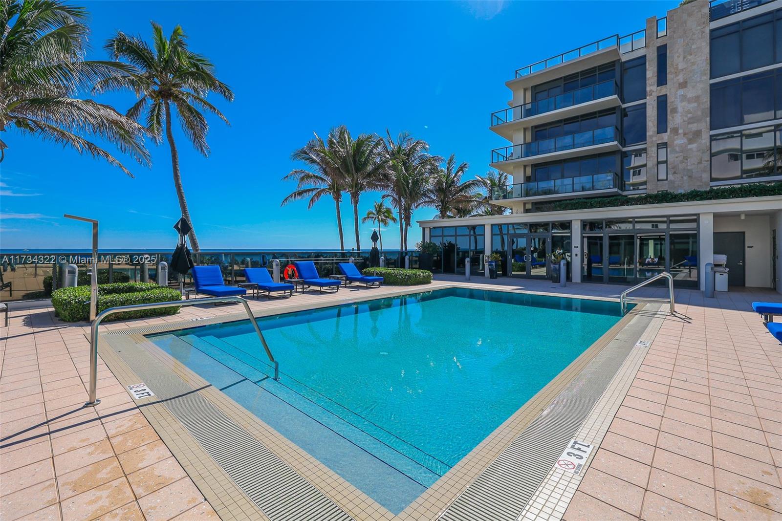 2205 South Surf Road, Unit 4A Hollywood, FL 33019 - Photo 59 of 71 a view of a swimming pool with a lawn chairs under palm trees