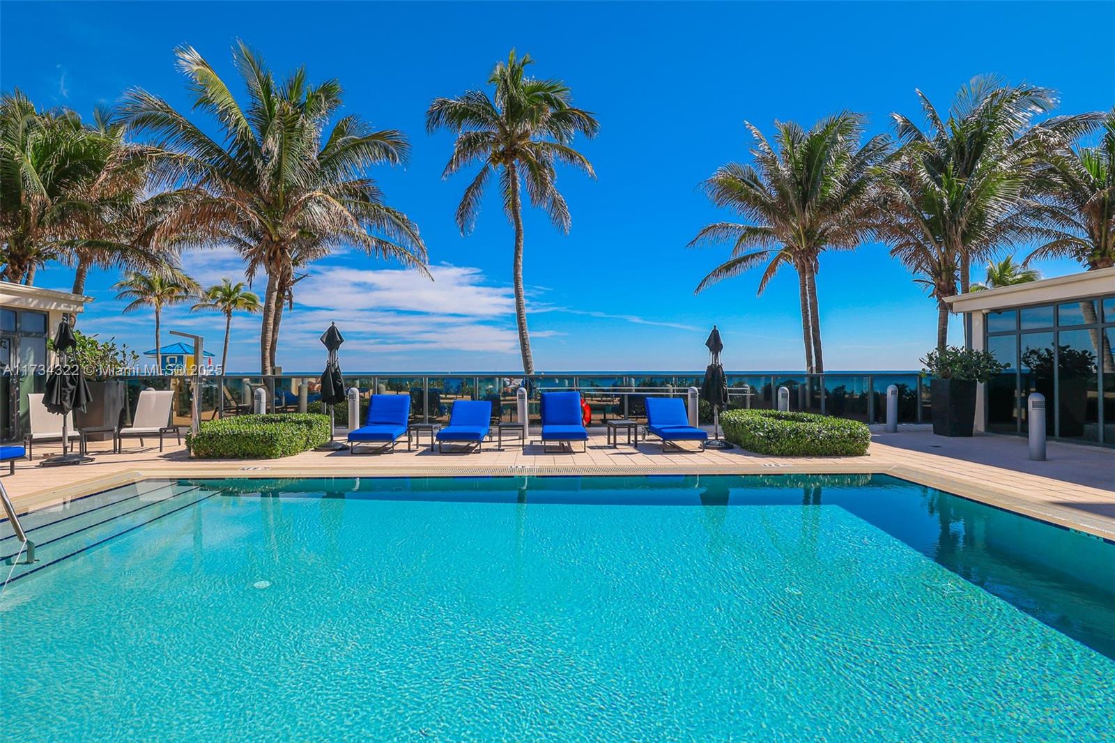 2205 South Surf Road, Unit 4A Hollywood, FL 33019 - Photo 61 of 71 a view of a swimming pool with a table and chairs under palm trees