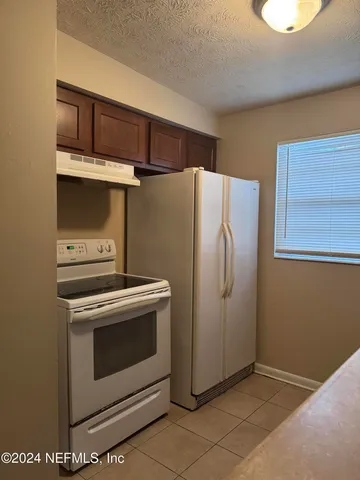 a view of a kitchen with refrigerator and cabinets