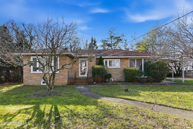 a front view of a house with garden and trees
