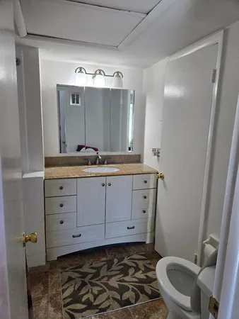 a bathroom with a granite countertop sink mirror vanity and toilet