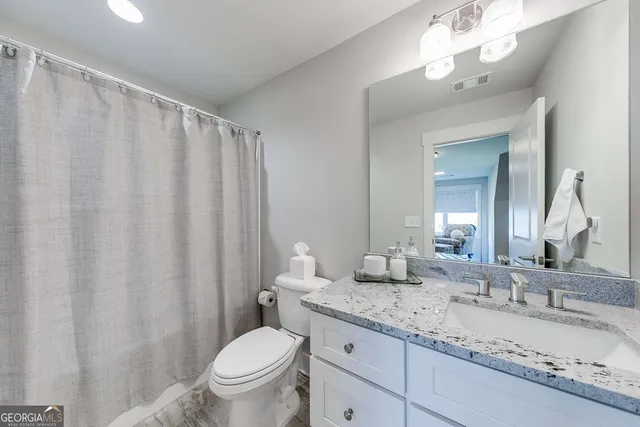 a bathroom with a granite countertop sink toilet and a mirror