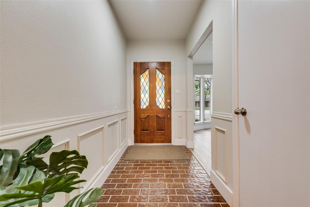 4801 Rock Ridge Court Arlington, TX 76017 - Photo 2 of 27 a hallway with wooden floor windows and chandelier