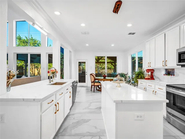 a kitchen with kitchen island sink stove and white cabinets