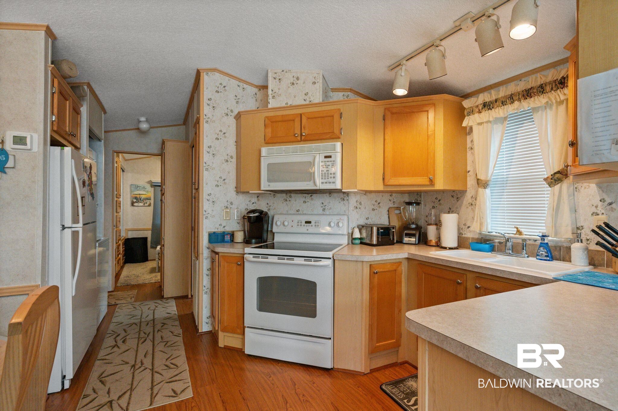 24711 County Road 20, Unit A11 Elberta, AL 36530 - Photo 12 of 35 Kitchen with white appliances, a textured ceiling, light wood-style floors, light countertops, and rail lighting
